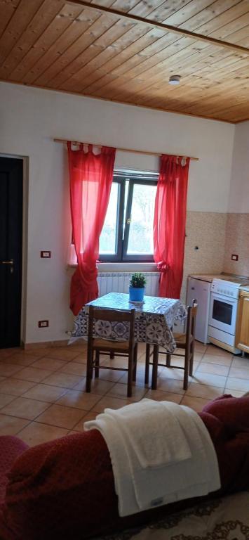 a living room with a table and red curtains at B&B La Foglietta in Paganica