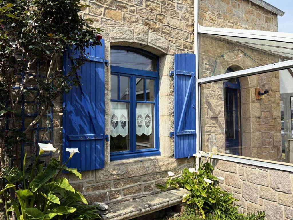 une fenêtre bleue sur le côté d'une maison en briques dans l'établissement Résidence C21-ile Grande - Jolie Maison de pêcheur au cœur de l'Ile Grande MAE-1293, à Pleumeur-Bodou