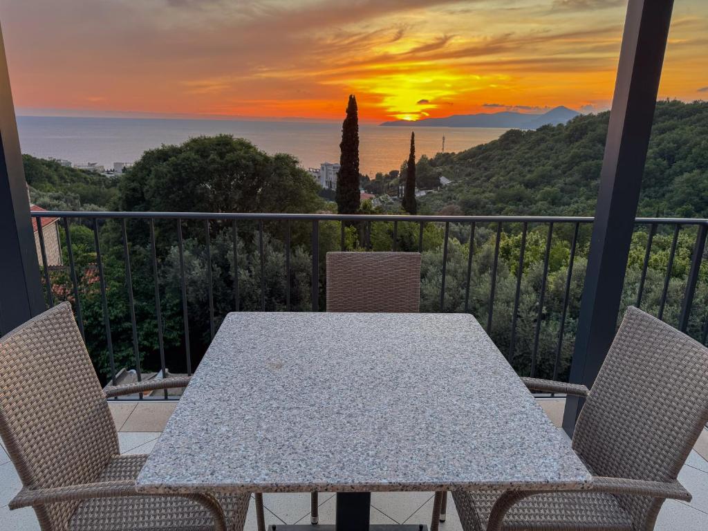 a table and chairs on a balcony with a sunset at Residence Vukovic, Rezevici in Reževići