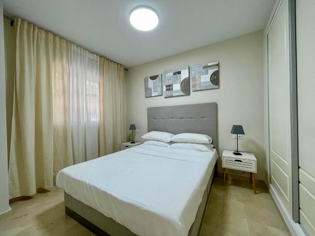 a bedroom with a large white bed and a window at Beachside Vacation Apartment in Casares Playa in San Luis de Sabinillas