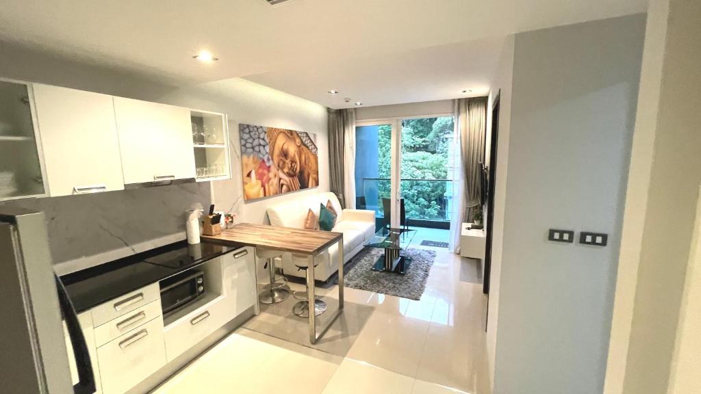 a kitchen with a table and a couch in a room at EMERALD TERRACE CONDO 52-FAMILY 1 Bedroom POOL VIEW in Patong Beach