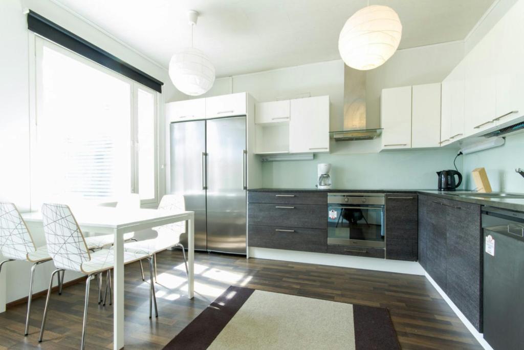 a kitchen with a table and chairs and a refrigerator at Spacious Apartment for 8 with Sauna in Kerava