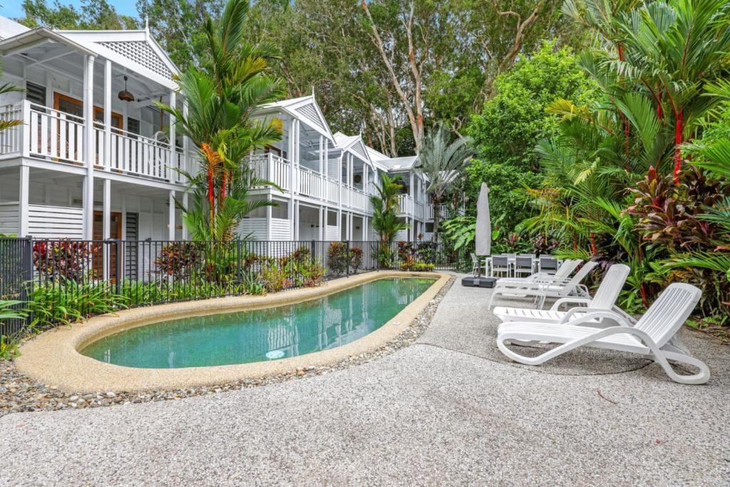 a house with a swimming pool and two lounge chairs at The Queenslander - Full Moon Terrace in Port Douglas
