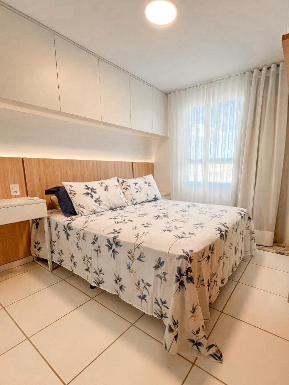 a bedroom with a bed with a white blanket and a window at 2Qts, 6km do Parque do Povo in Campina Grande