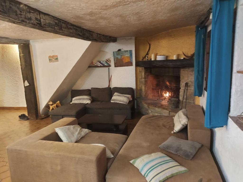 un salon avec un canapé et une cheminée dans l'établissement Maison de Montagne chaleureuse, à Gréolières