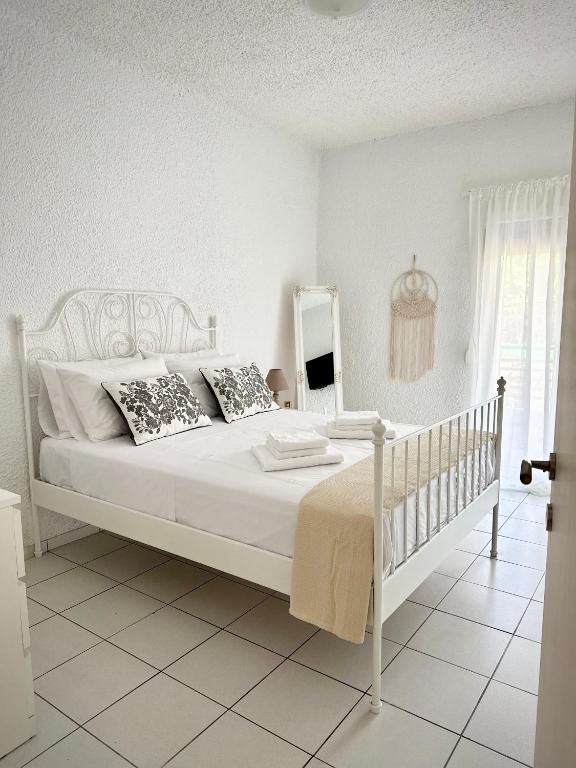 Un dormitorio blanco con una cama blanca y un espejo. en Pap's Summer House, en Polychrono