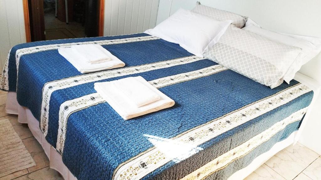 a bed with blue and white sheets and pillows at Recanto do Sossego II - Sheriff's House in Santa Cruz do Sul