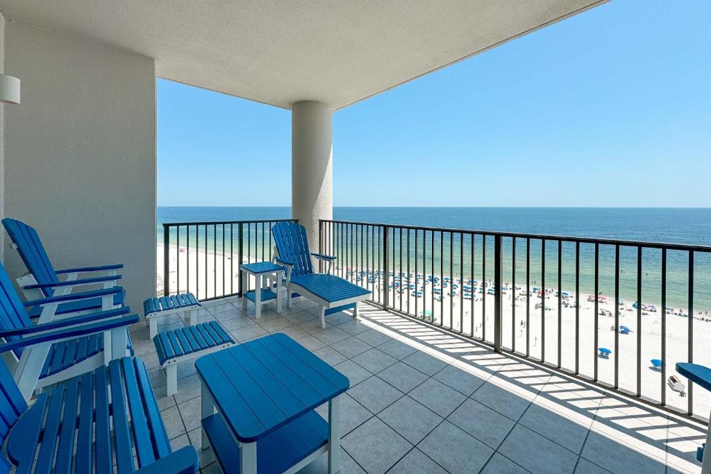 a balcony with blue chairs and a view of the beach at The Oasis at Orange Beach Unit 905 in Orange Beach