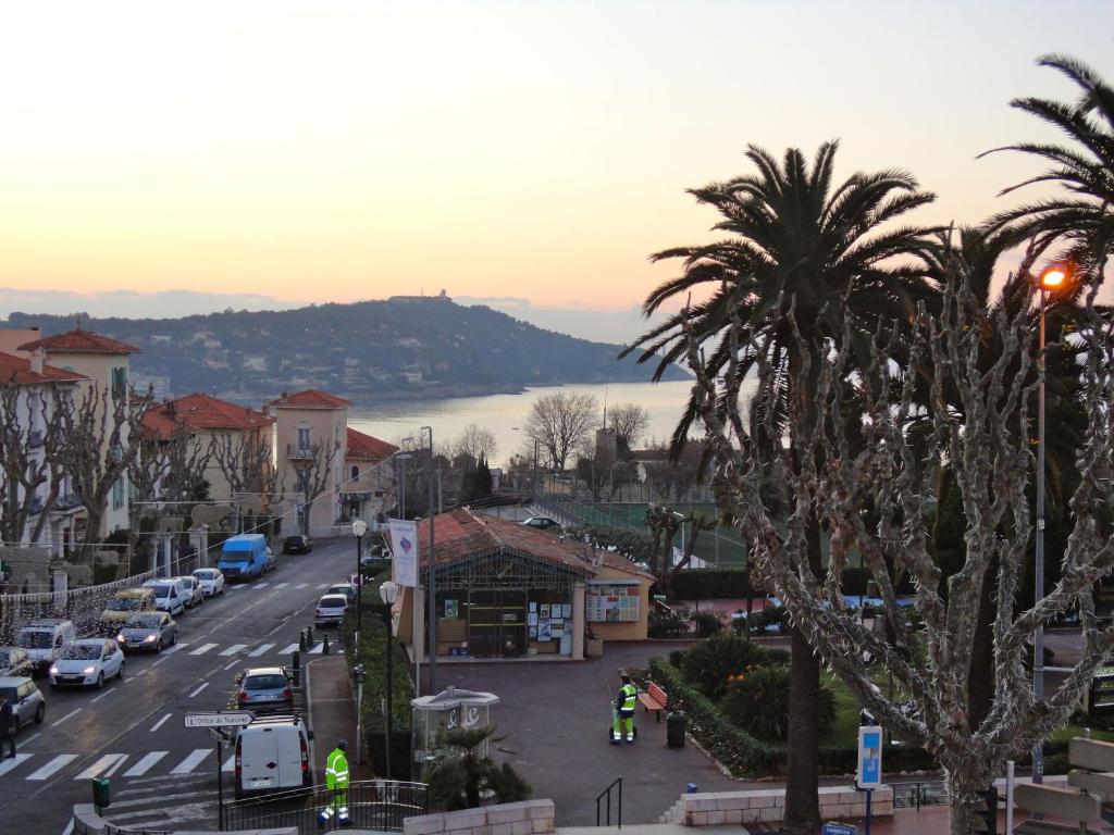 a city street with palm trees in a town at Hotel La Regence in Villefranche-sur-Mer