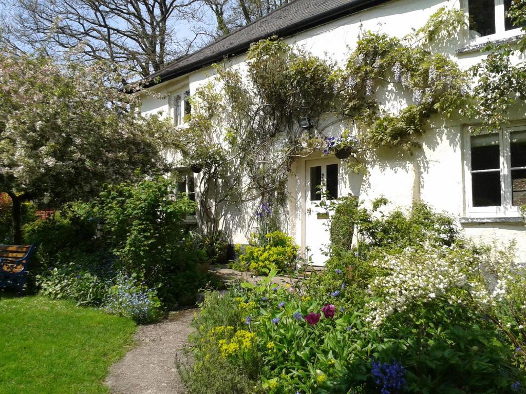 a white house with flowers in front of it at Tracebridge Cottage B&B in Stawley
