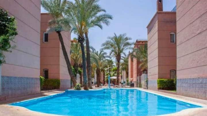 a swimming pool with palm trees and a building at Riad Four Rooms & Pool in Marrakesh