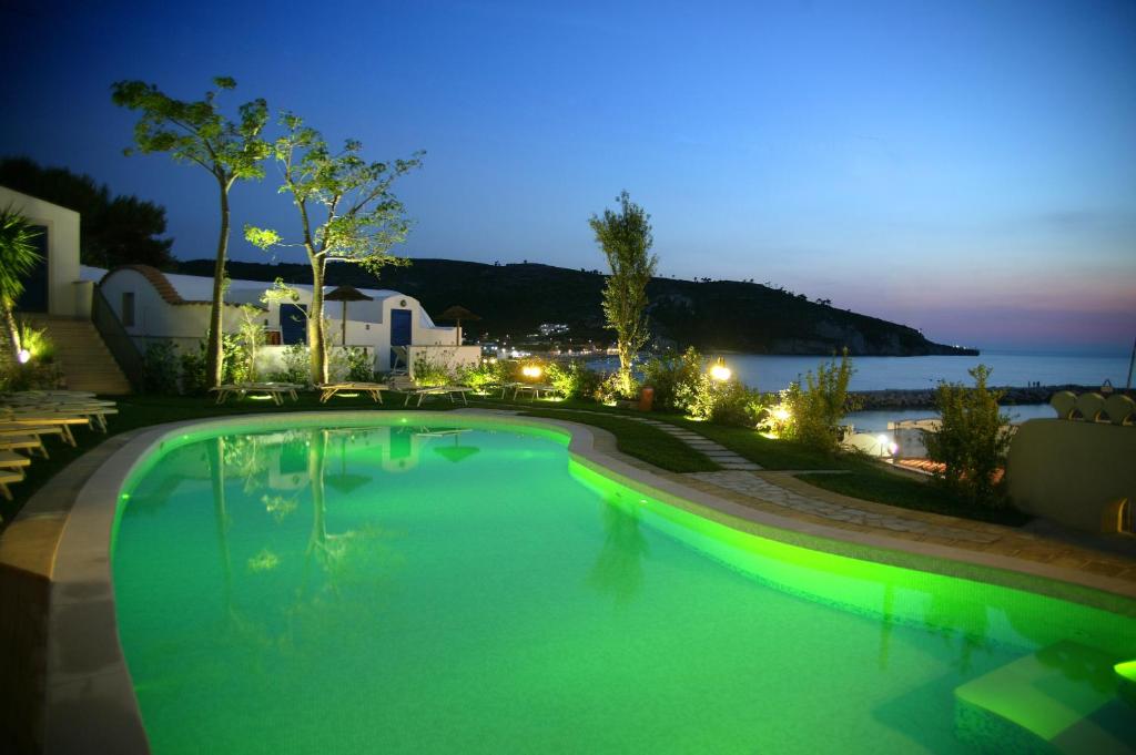 a swimming pool at night with the ocean in the background at Hotel Elisa - Spiaggia Privata Inclusa in Peschici