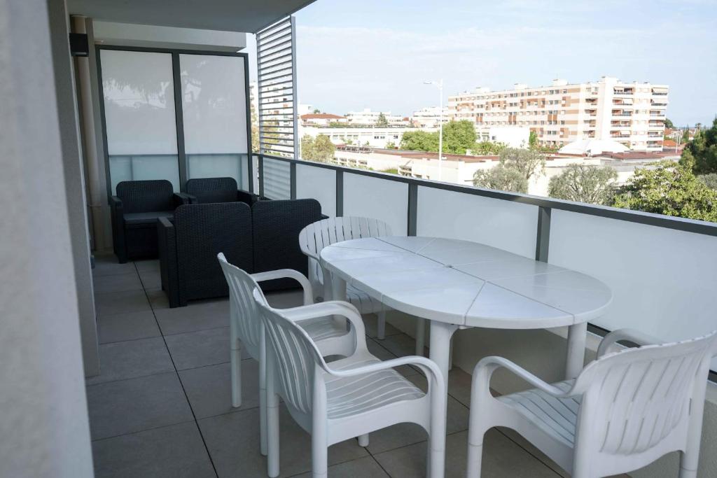 une table blanche et des chaises sur un balcon avec vue dans l'établissement Sea view apartment close to beaches, à Cagnes-sur-Mer
