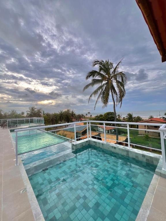 a swimming pool on top of a building with a palm tree at Del Mar SG Apartment in Trairi