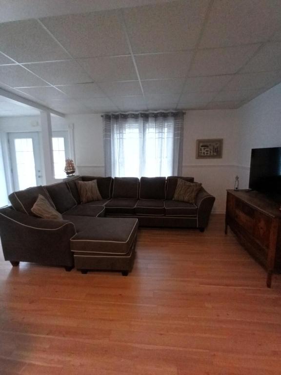 a living room with a couch and a tv at Le Narval Hébergement Touristique in Saint-Siméon
