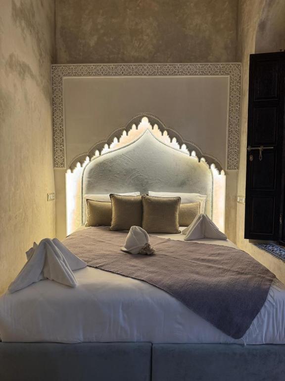 a large white bed with a large headboard in a bedroom at Riad M'Barka in Tangier