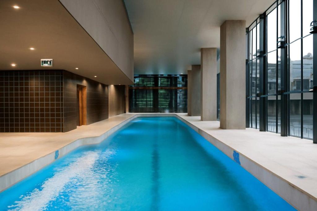 an indoor pool with blue water in a building at Spencer St Serenity Stylish Urban Escape in the CBD in Melbourne