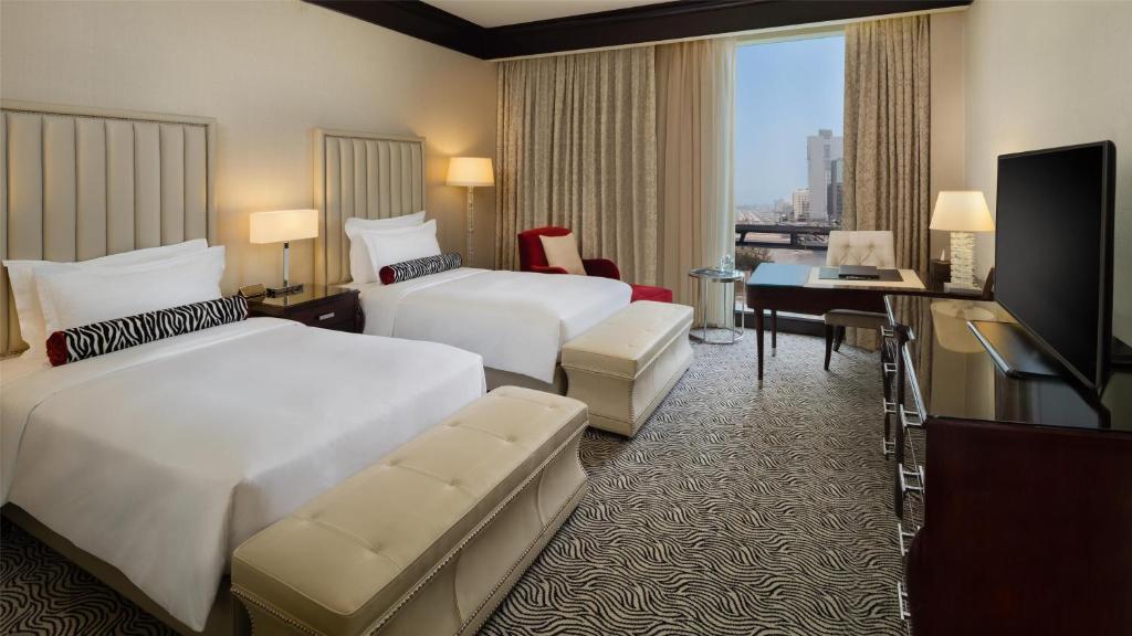 a hotel room with two beds and a television at Kempinski Al Othman Hotel Al Khobar in Al Khobar