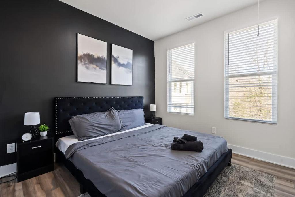 a bedroom with a bed and two windows at Luxurious King 3BR Townhouse Mins to Uptown CLT! in Charlotte