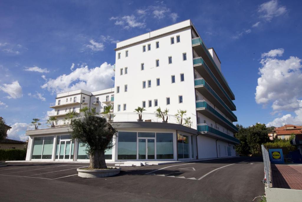 un edificio blanco con un árbol en un estacionamiento en Residence Le Stelle, en Campolungo
