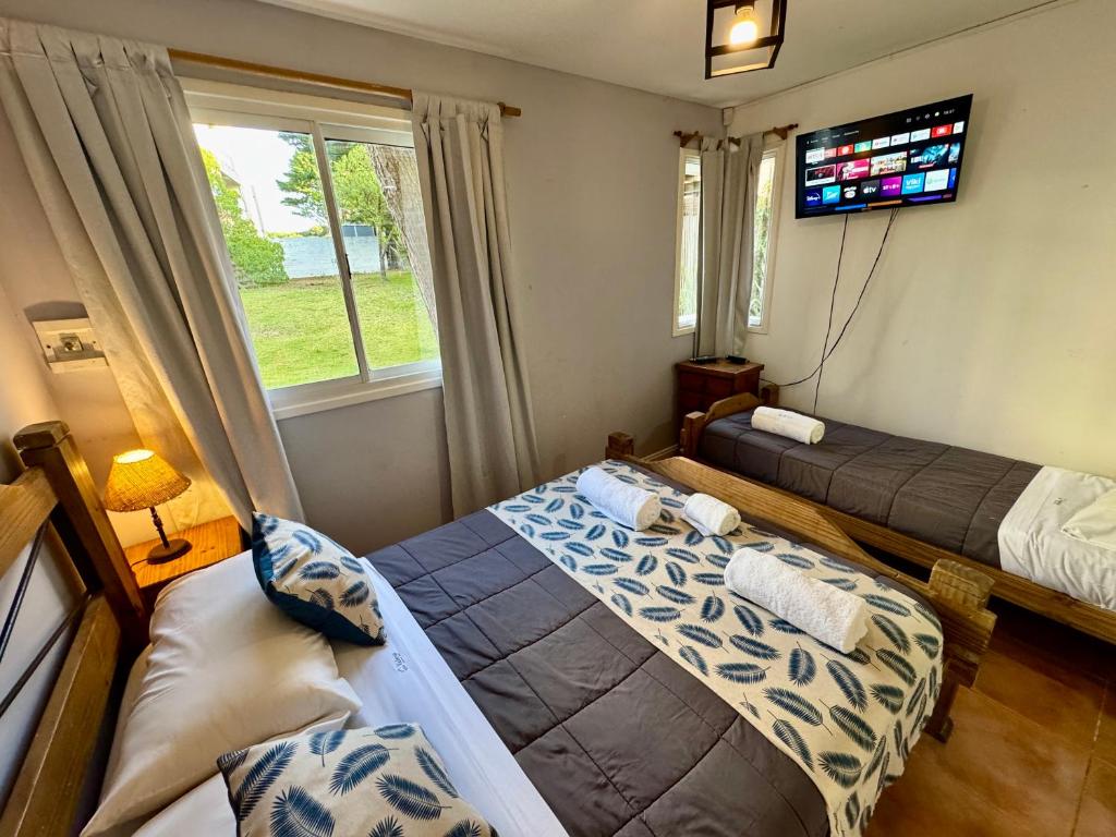 a bedroom with two beds and a tv on the wall at Valeria Costa y Mar in Valeria del Mar