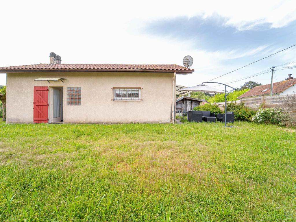 a small house with a red door in a yard at Maison de vacances à Lit-et-Mixe pour 4 pers. - Calme et nature avec jardin inclus - FR-1-50-176 in Lit-et-Mixe