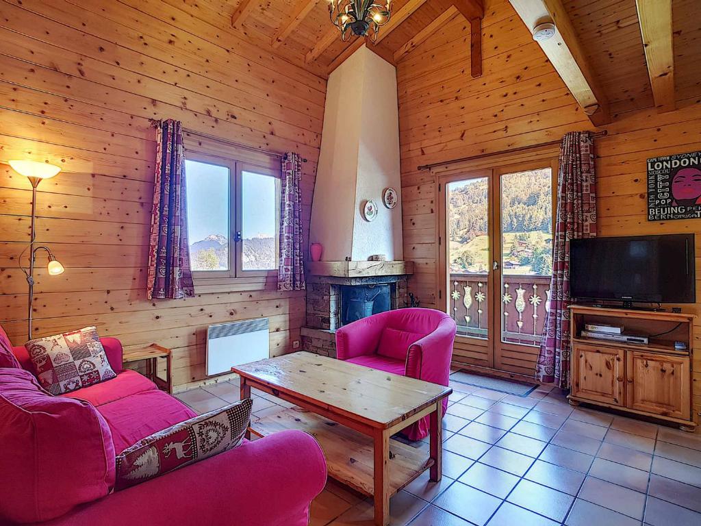 - un salon avec des chaises roses, une table et une télévision dans l'établissement Demi-chalet cosy à La Clusaz pour 6 pers, cheminée, animaux admis, WiFi - FR-1-818-102, à La Clusaz