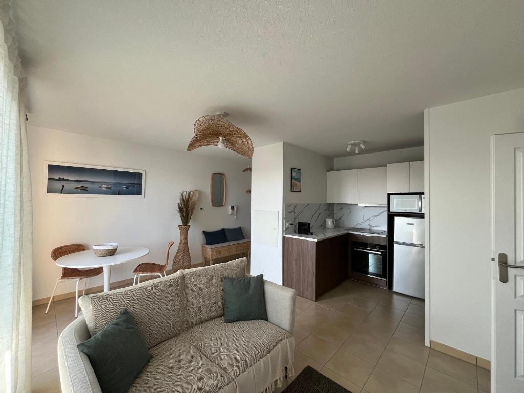 un salon et une cuisine avec un canapé et une table dans l'établissement T2 lumineux en centre-ville avec balcon et parking sécurisé - FR-1-319-612, à La Teste-de-Buch