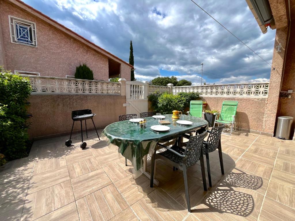 un patio avec une table et des chaises sur une terrasse dans l'établissement Maison familiale climatisée avec terrasse près de la plage, Saint-Cyprien - FR-1-309-510, à Saint-Cyprien