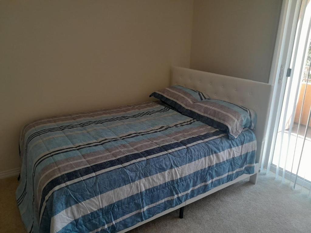 a small bed in a bedroom with a striped blanket at Great place for good night rest in Anaheim