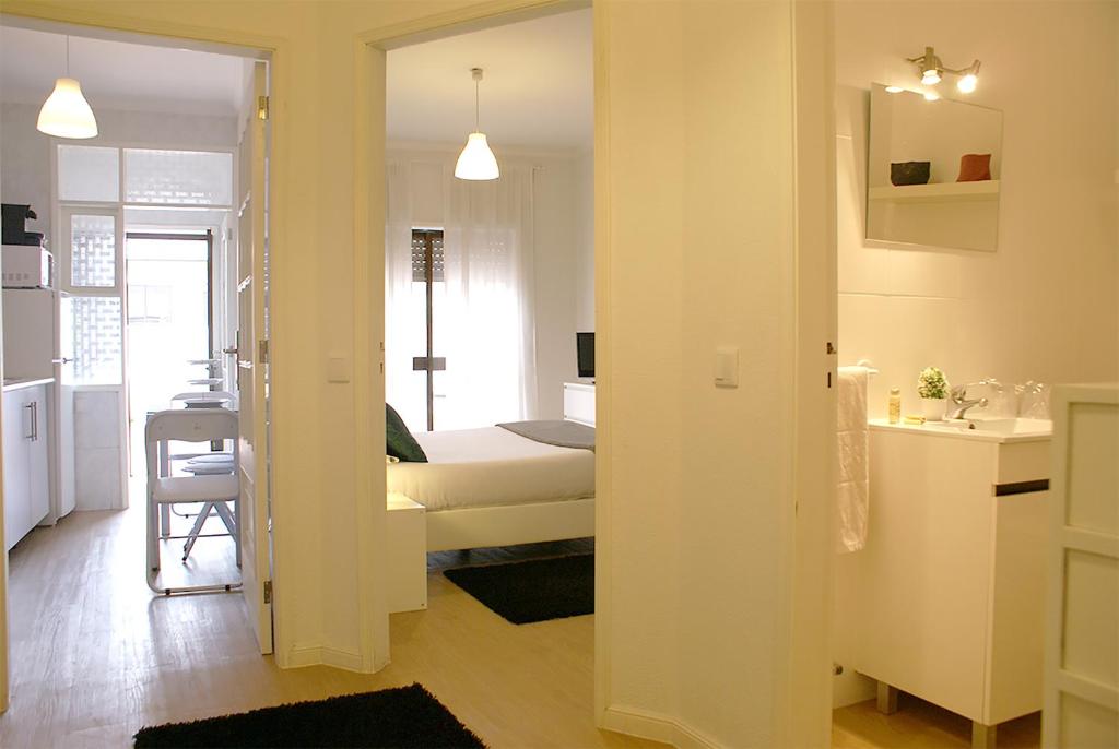 a bedroom with a bed and a bathroom with a sink at Nove Julho Apartment in Porto