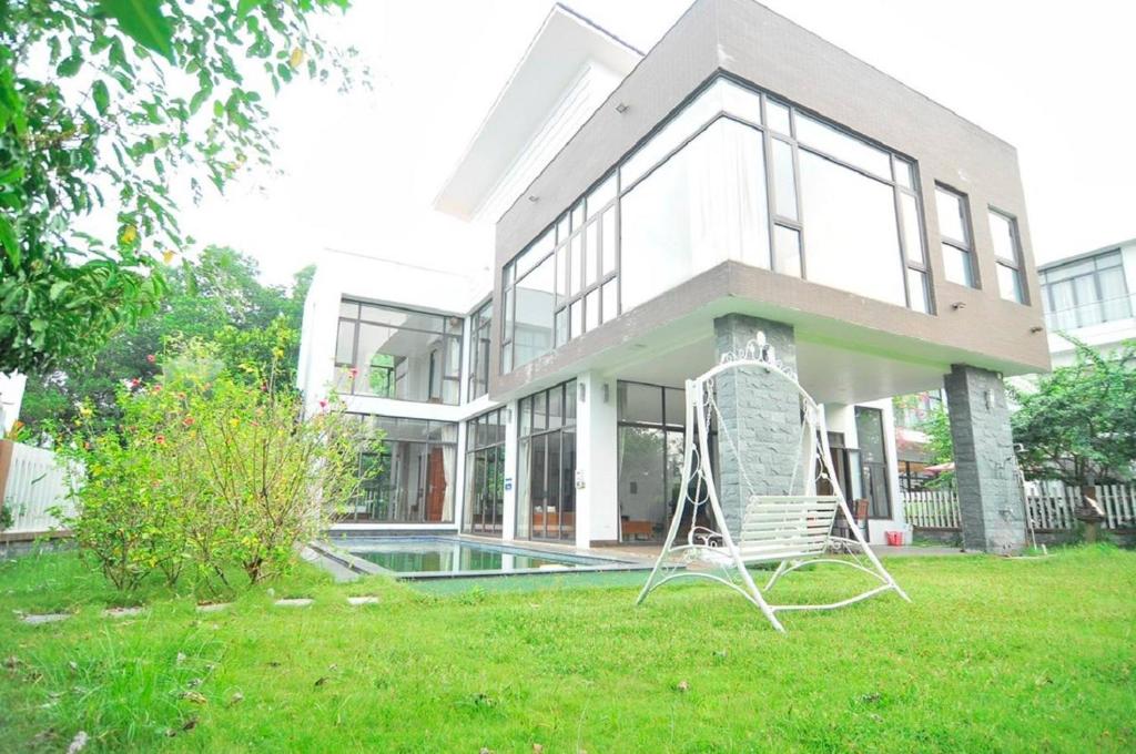 une chaise blanche assise devant une maison dans l'établissement Villa T100 - 5 phòng ngủ Chủ Tự Doanh tại FLAMIGO ĐẠI LẢI RESORT, à Phúc Yên