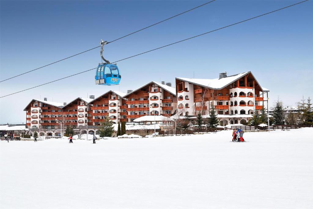 people on a ski lift in front of a ski resort at Kempinski Hotel Grand Arena Bansko in Bansko