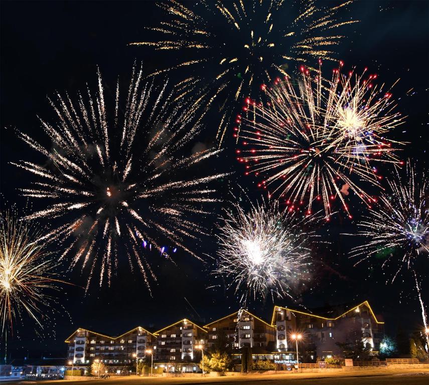 a group of fireworks in the sky over houses at Kempinski Hotel Grand Arena Bansko in Bansko