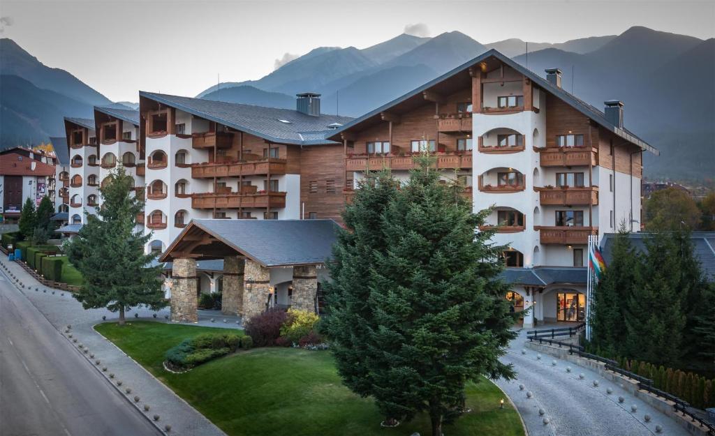 a large building with mountains in the background at Kempinski Hotel Grand Arena Bansko in Bansko