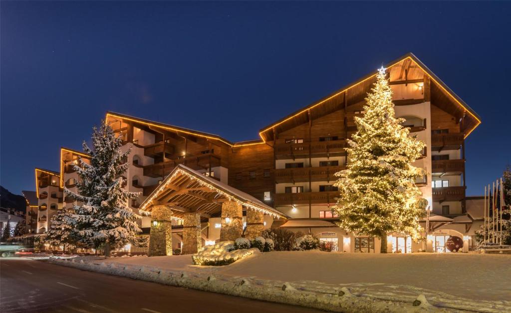 a building with a christmas tree in front of it at Kempinski Hotel Grand Arena Bansko in Bansko