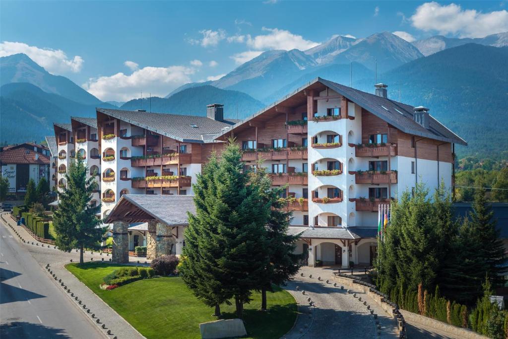 a large apartment building with mountains in the background at Kempinski Hotel Grand Arena Bansko in Bansko