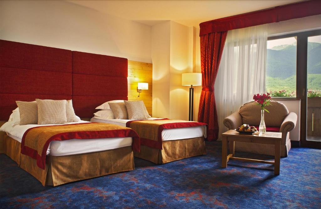 a hotel room with two beds and a chair at Kempinski Hotel Grand Arena Bansko in Bansko