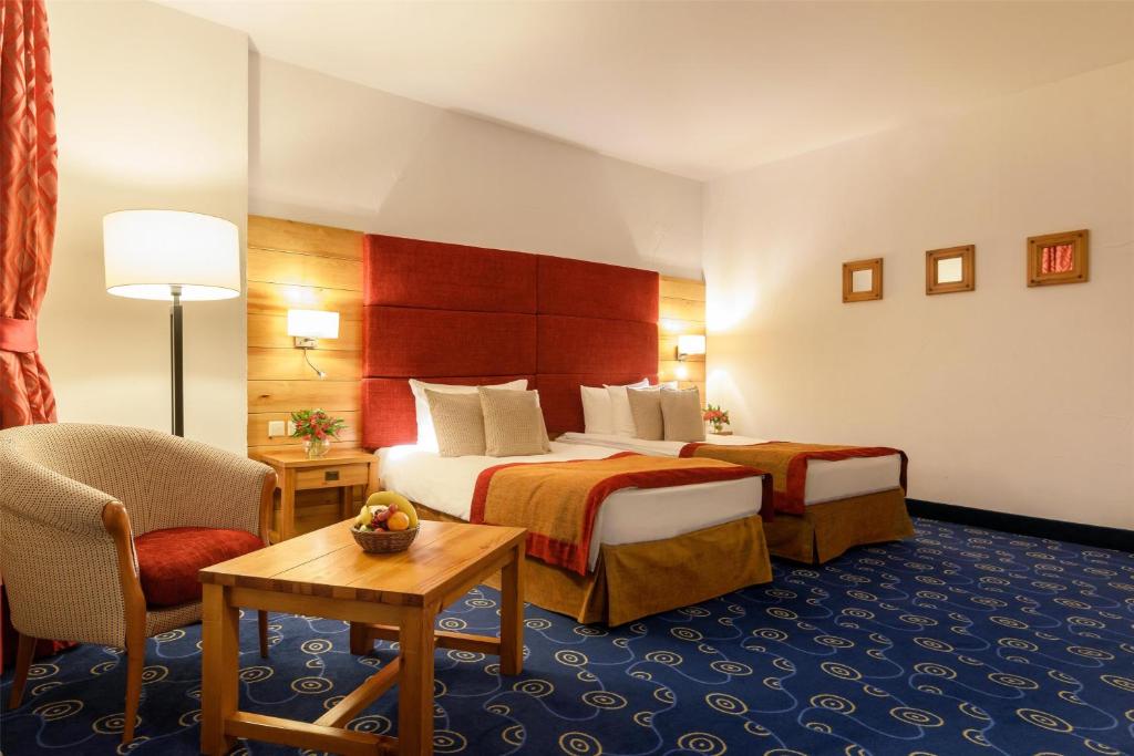 a hotel room with two beds and a chair at Kempinski Hotel Grand Arena Bansko in Bansko