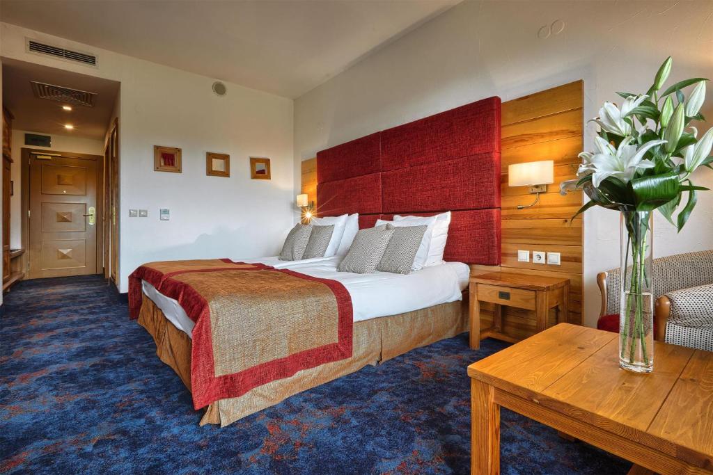 a hotel room with a large bed and a table at Kempinski Hotel Grand Arena Bansko in Bansko