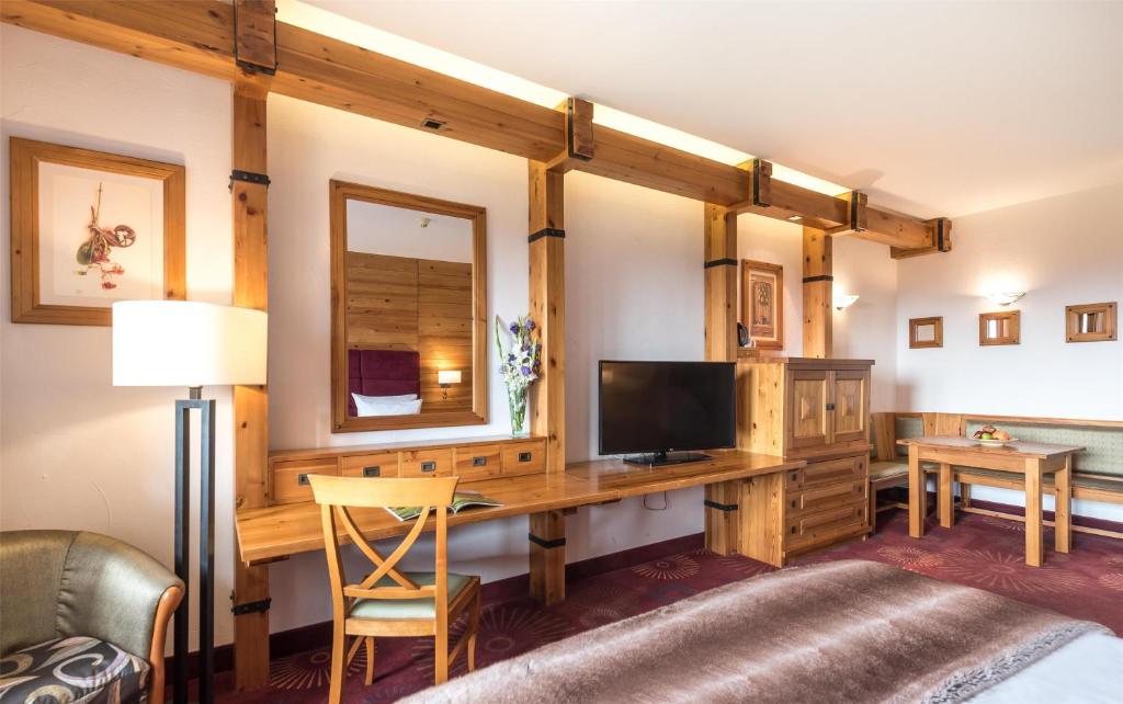 a living room with a desk with a television at Kempinski Hotel Grand Arena Bansko in Bansko