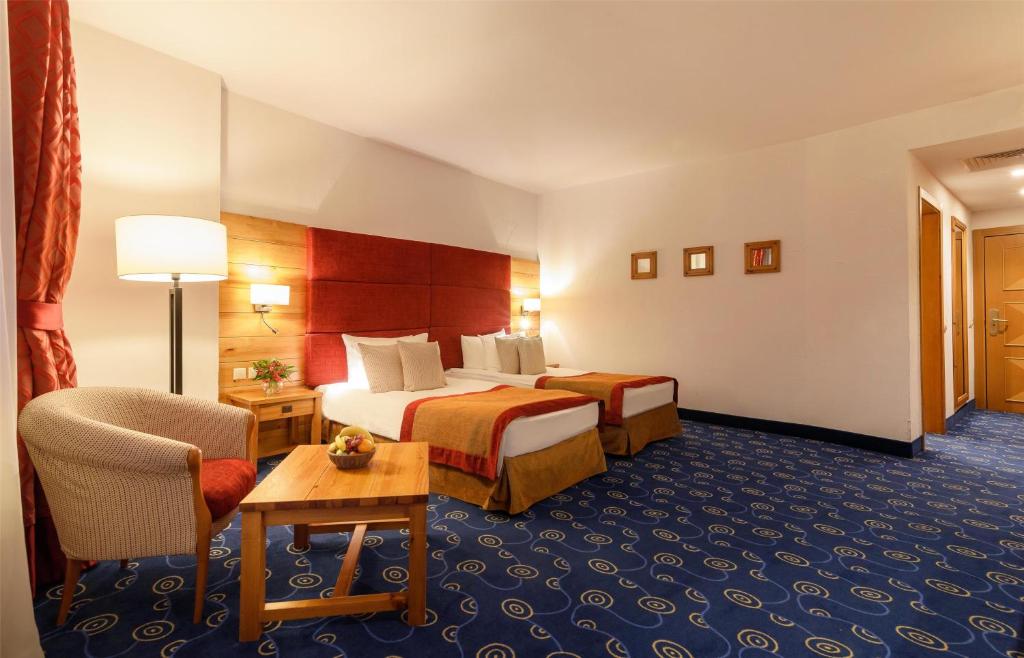 a hotel room with two beds and a chair at Kempinski Hotel Grand Arena Bansko in Bansko