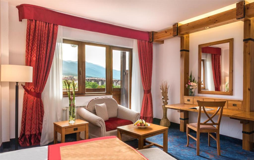a hotel room with a bed and a table and chairs at Kempinski Hotel Grand Arena Bansko in Bansko
