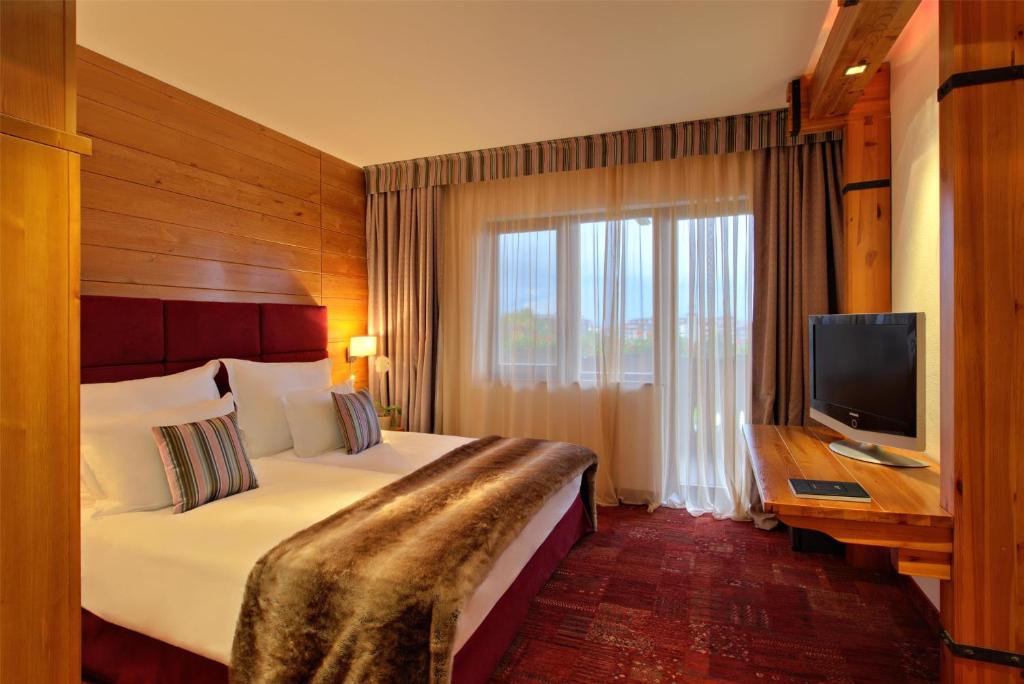 a hotel room with a bed and a television at Kempinski Hotel Grand Arena Bansko in Bansko