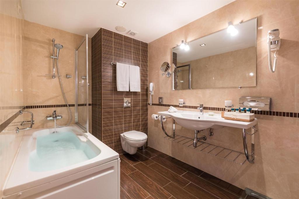 a bathroom with a tub and a sink and a toilet at Kempinski Hotel Grand Arena Bansko in Bansko