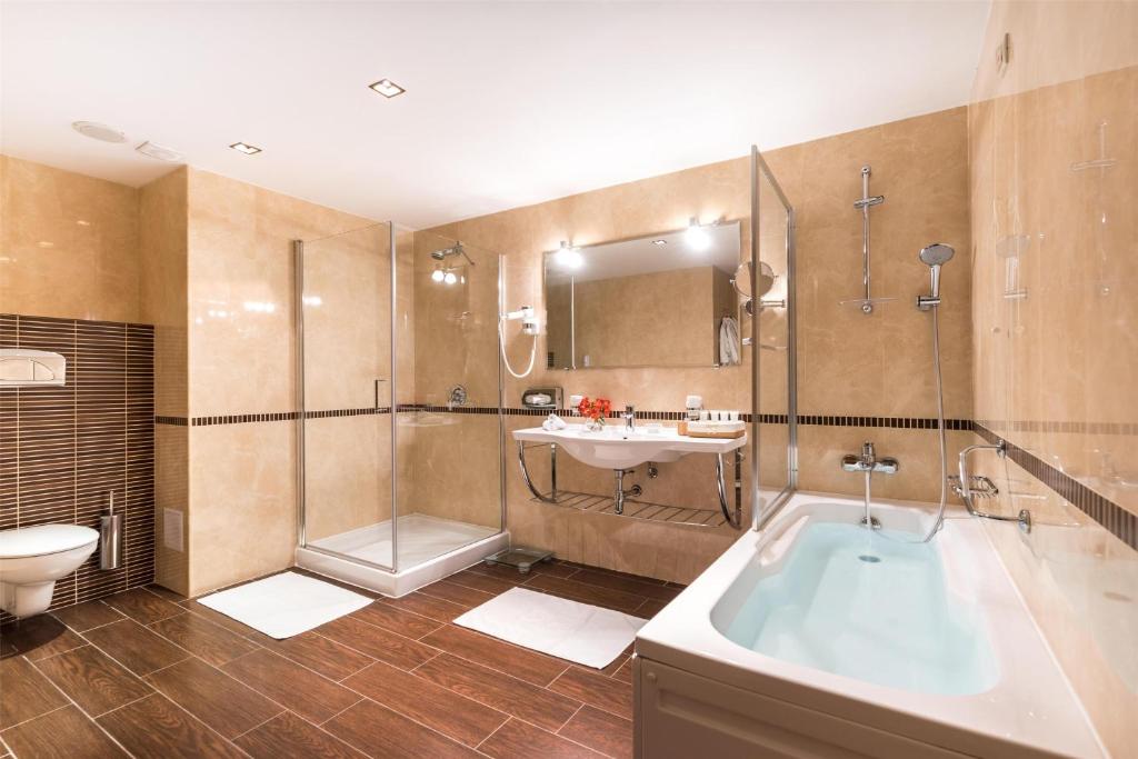 a bathroom with a tub and a toilet and a sink at Kempinski Hotel Grand Arena Bansko in Bansko