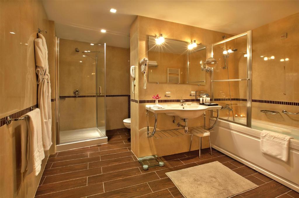 a bathroom with a sink and a shower and a toilet at Kempinski Hotel Grand Arena Bansko in Bansko