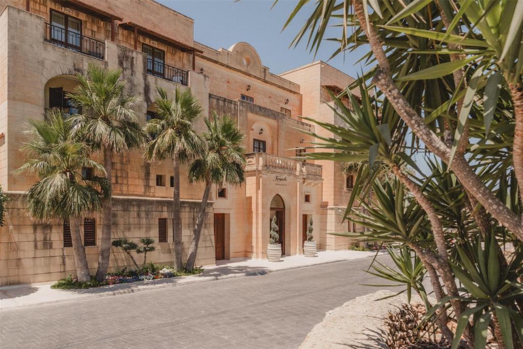 a building with palm trees in front of a street at Kempinski Hotel San Lawrenz in San Lawrenz