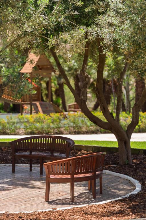 two benches in a park with trees and a gazebo at Kempinski Hotel San Lawrenz in San Lawrenz
