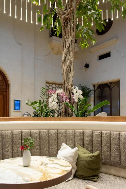a table with a tree in the middle of a room at Kempinski Hotel San Lawrenz in San Lawrenz